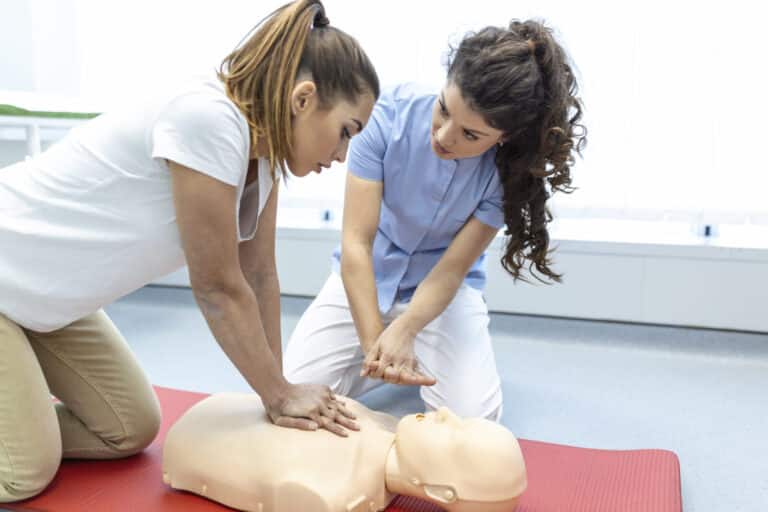 Zwei Frauen üben gemeinsam die Herzdruckmassage an einer Übungspuppe