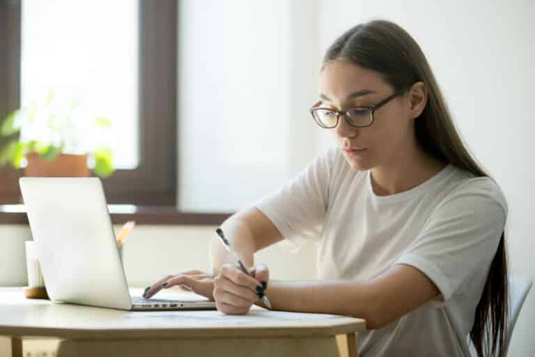 Junge Frau lernt am Laptop und macht sich Notizen